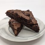 Gluten-free vegan chocolate chip brownie slices stacked on a white marble plate